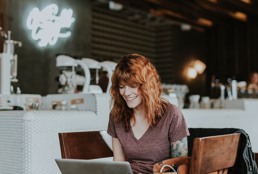 Red header woman sits at table planning ESG activities on laptop