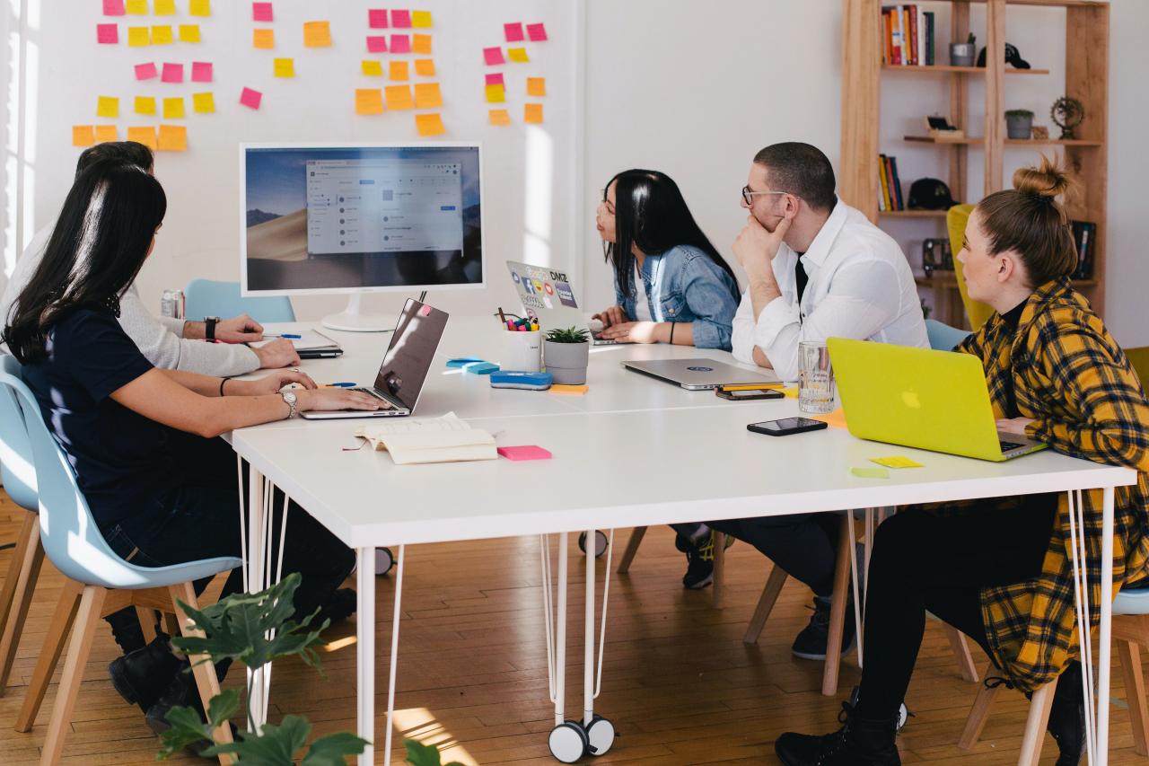 Five people sit making business plans at a desk