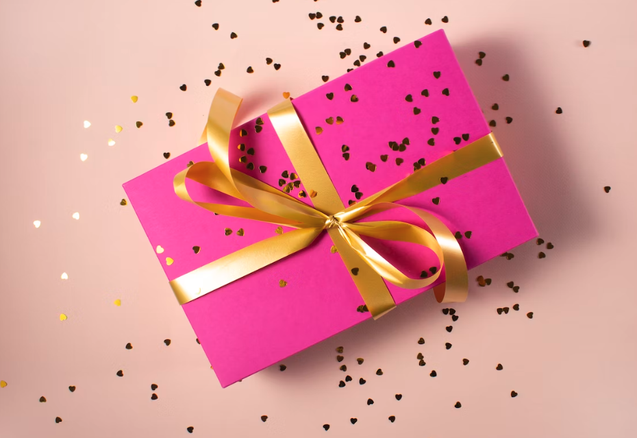 What is Corporate Donation Matching? (A gift is wrapped in pink paper, tied with gold ribbon and sprinkled with golden confetti)